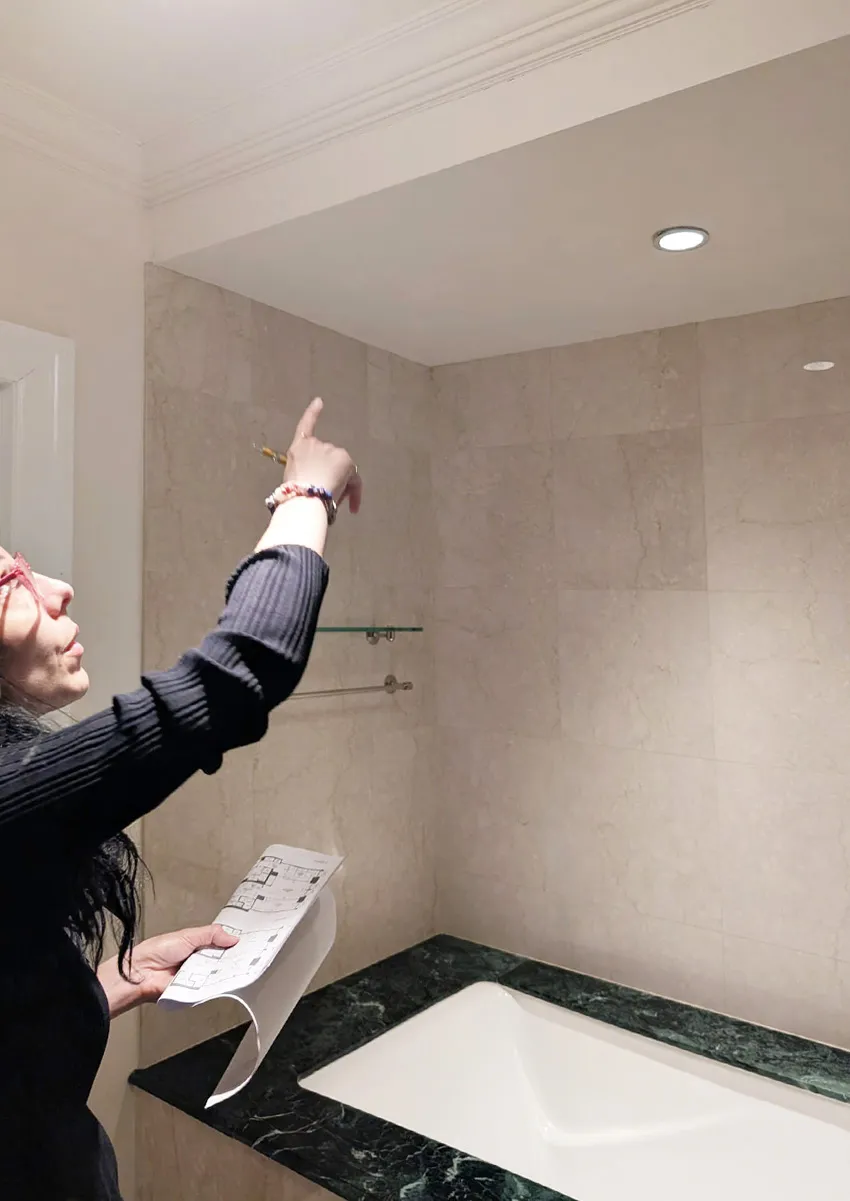 Lenka Ilic, Principal Architect, reviewing existing bathroom tile and ceiling conditions during a NYC co-op apartment survey