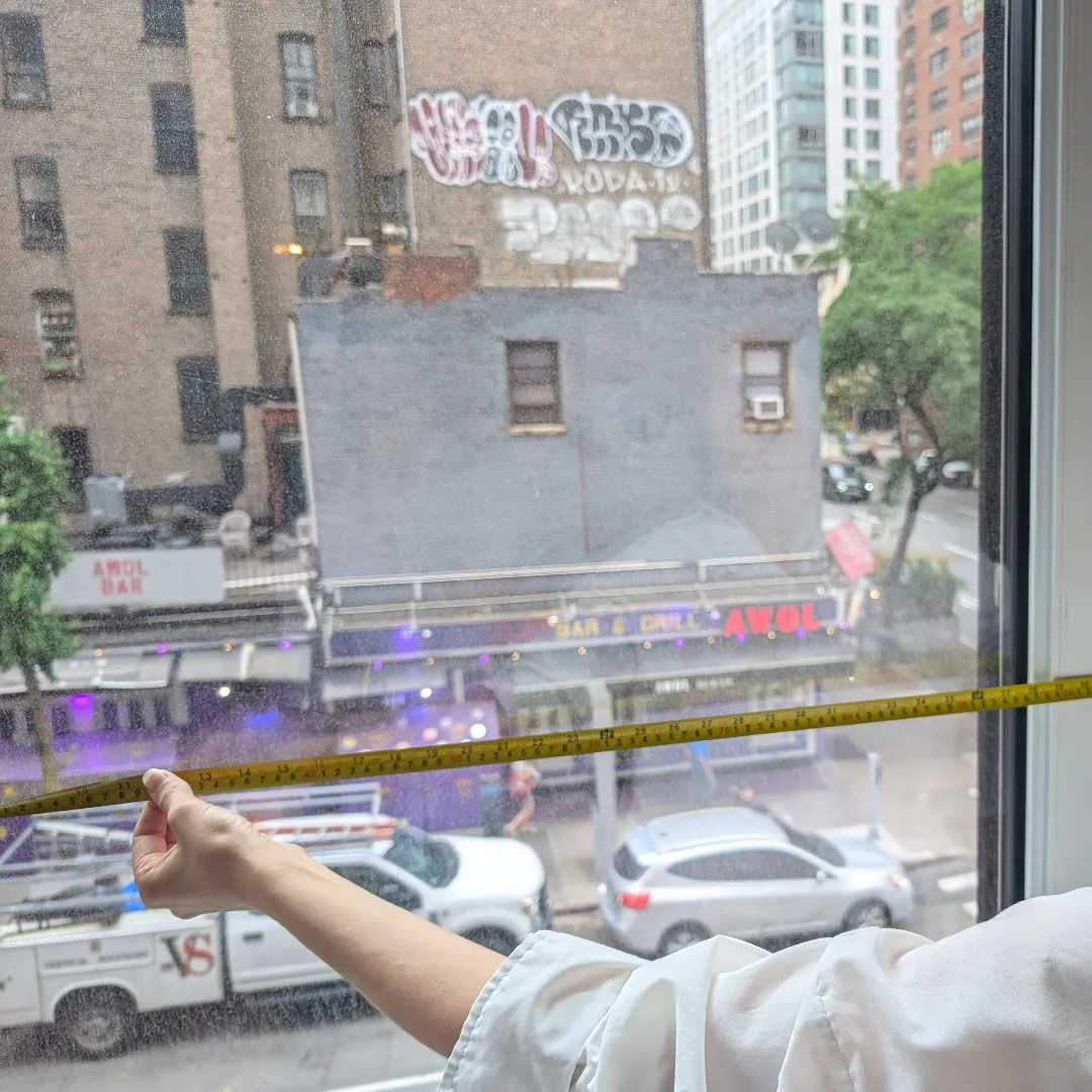 Co-op and condo board approval survey: Architect measuring an existing window opening with a tape measure in a NYC apartment