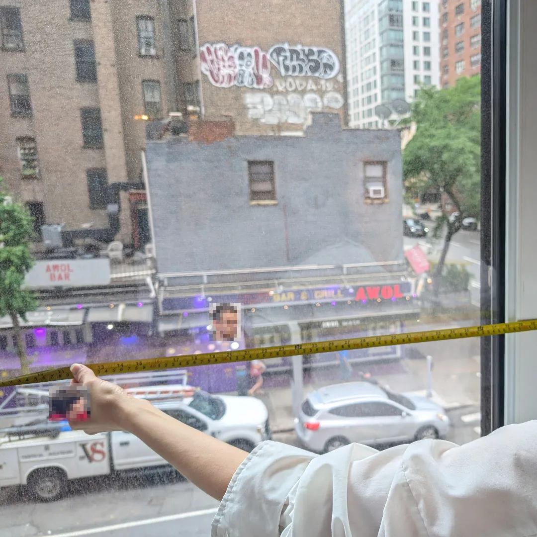 Architect measuring an existing window opening with a tape measure during a NYC co-op apartment existing conditions survey