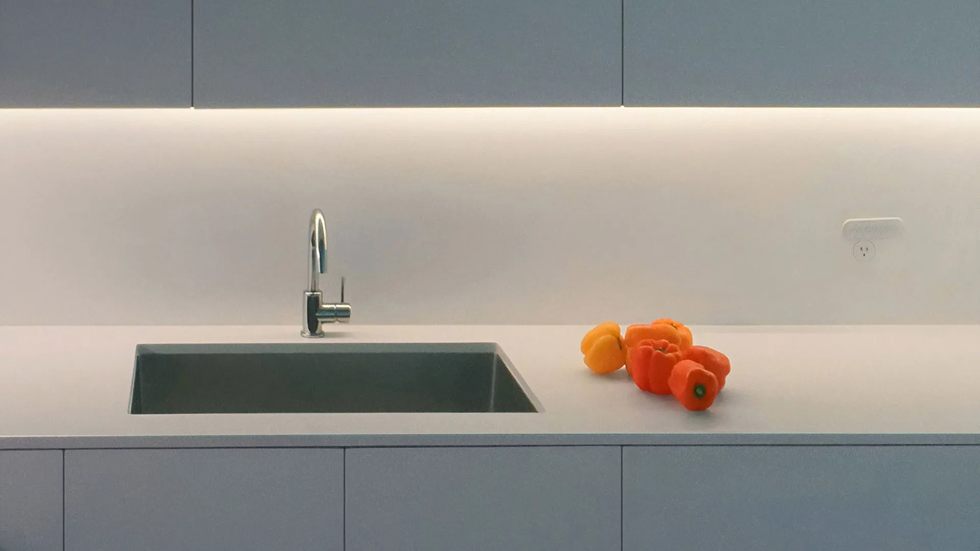 Blue-grey handleless kitchen cabinets and a stone countertop with an undermount sink in a renovated NYC apartment