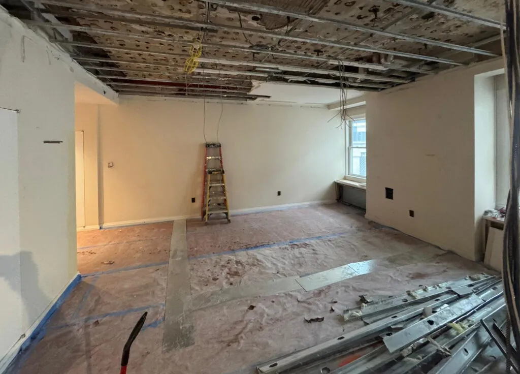 Gut renovation at prewar historic 55 Wall Street condo showing an open apartment interior, stacked steel studs, and protected flooring.