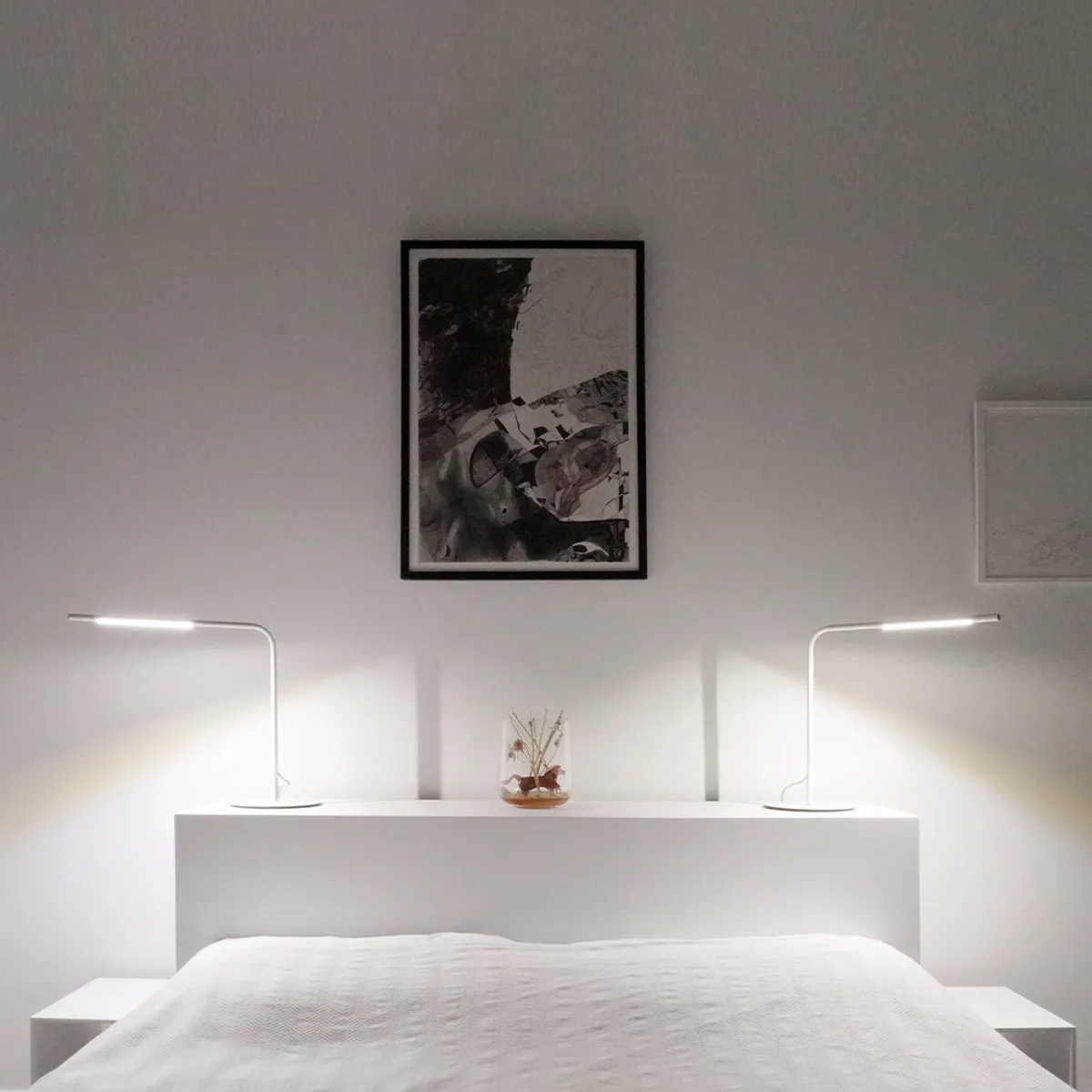 Modern Minimalist bedroom interior with white bedding, nightstands, a console, and artwork above the bed.