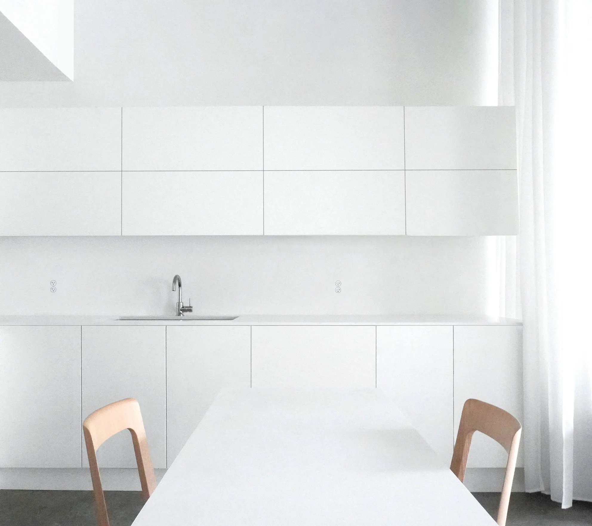NYC condo renovation kitchen design inspiration with white slab cabinets, a slim stone countertop, and Hiroshima dining chairs.